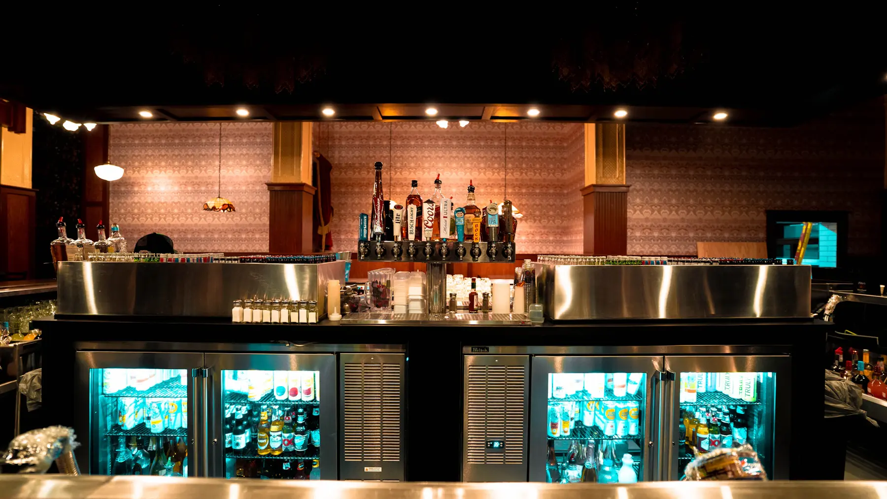 Bottles and warm lights behind a neighbourhood bar