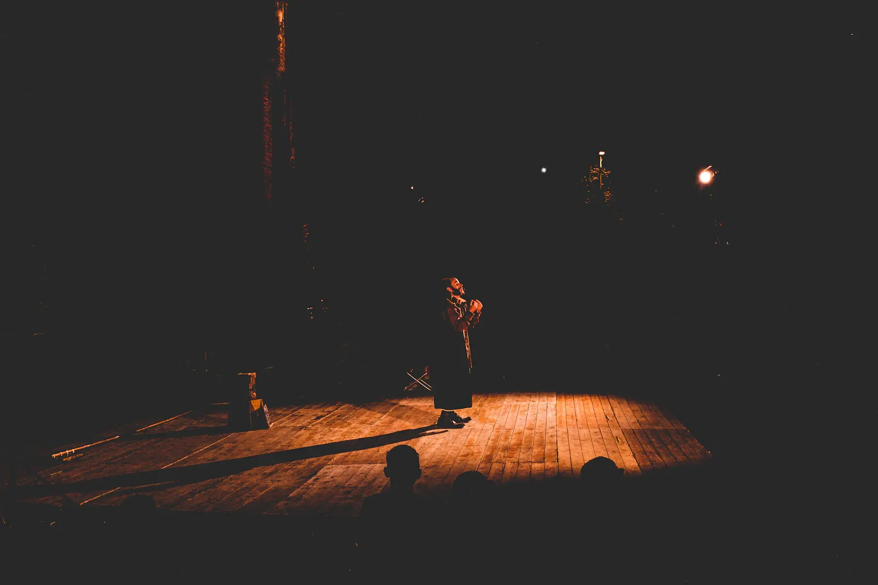 A solo performer on an intimate, warmly lit stage
